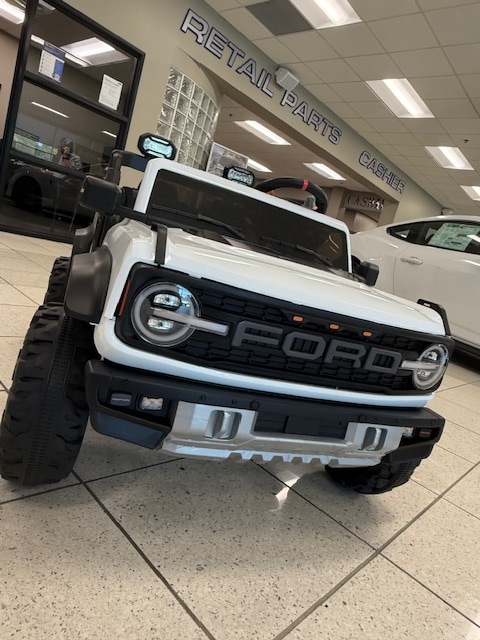 White 24-volt Ford Bronco Raptor ride-on toy on display in the Friendly Ford parts department