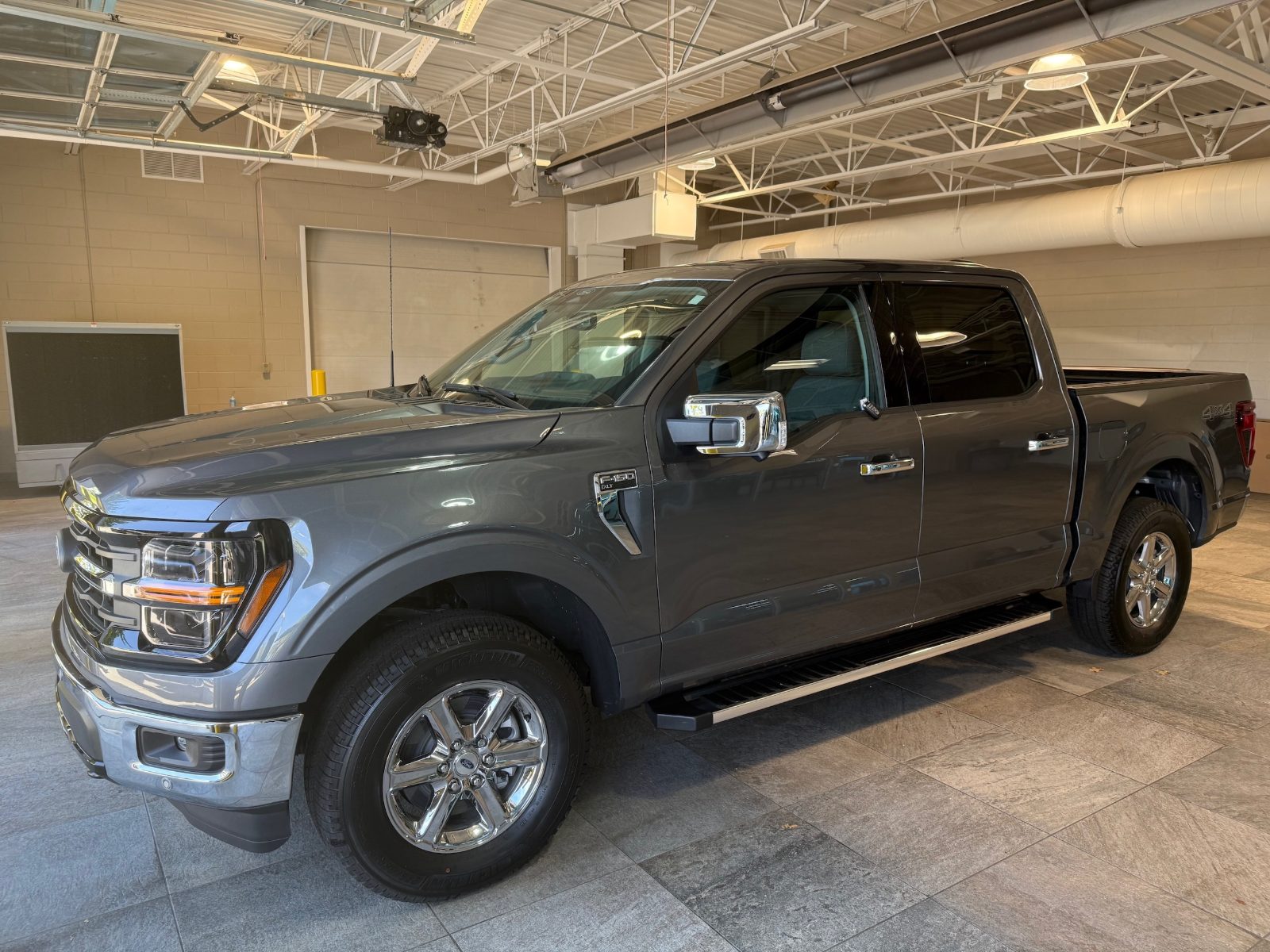 2025 Ford F-150 XLT in Carbonized Gray parked inside the Friendly Ford delivery bay