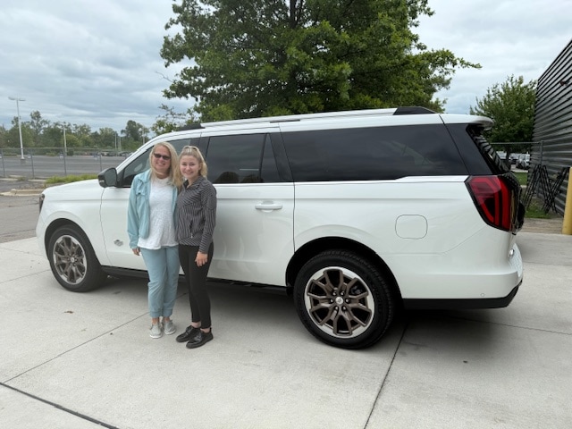 Cynthia and her Friendly Ford salesperson standing beside her new white 2025 Ford Expedition King Ranch
