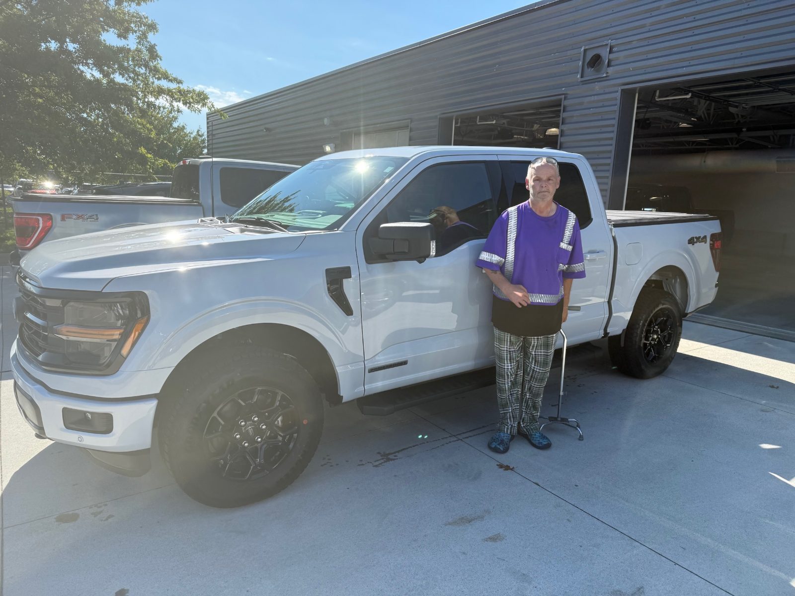 Joseph standing beside his new 2025 Ford F-150 XLT in Space White outside Friendly Ford
