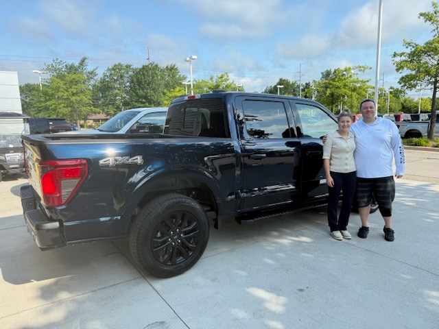 Nicholas and his Friendly Ford salesperson standing beside his new black Ford F-150 4x4