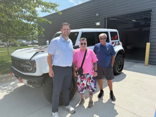 Three people standing in front of Tammy's new white 2025 Ford Bronco Raptor at Friendly Ford